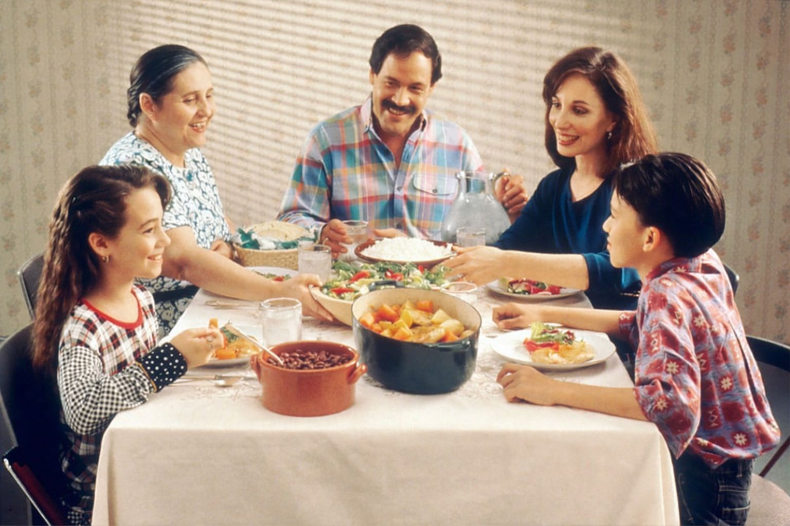 Smilende familie spiser middag ved et bord fyldt med mad.